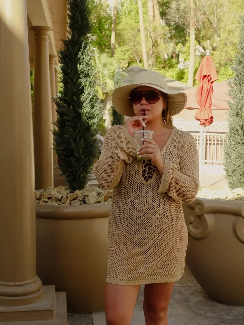 Crochet cover-up and wide-brim hat with an iced drink